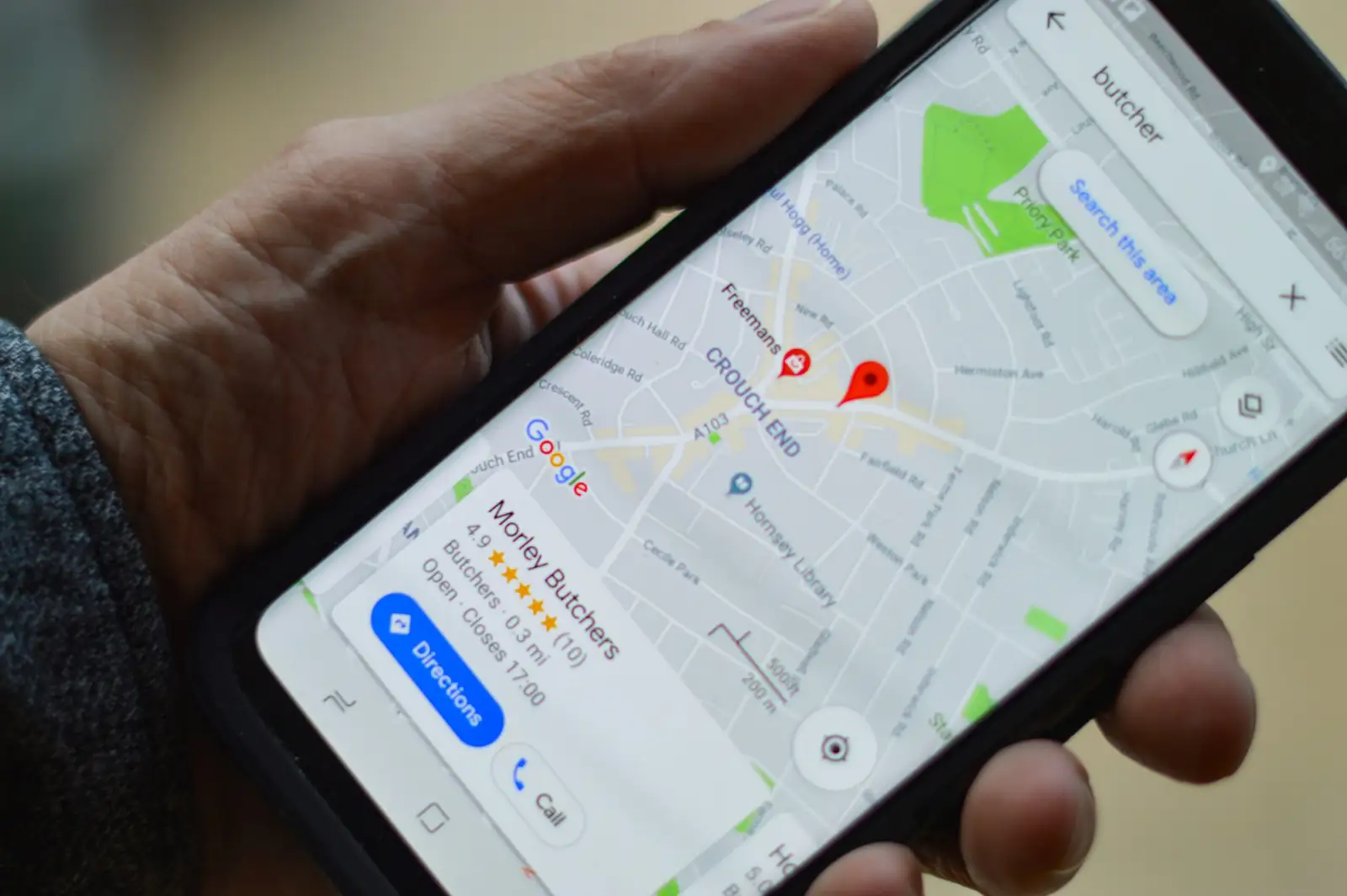 Main tenant un smartphone affichant Google Maps avec un commerce local géolocalisé